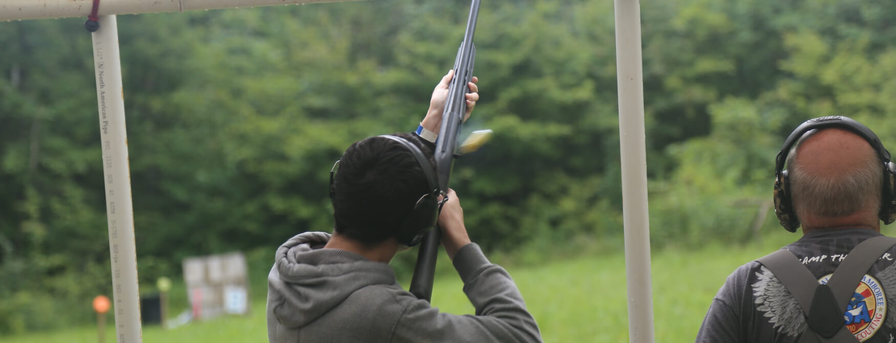 A Scout shoots a shotgun at the camp range